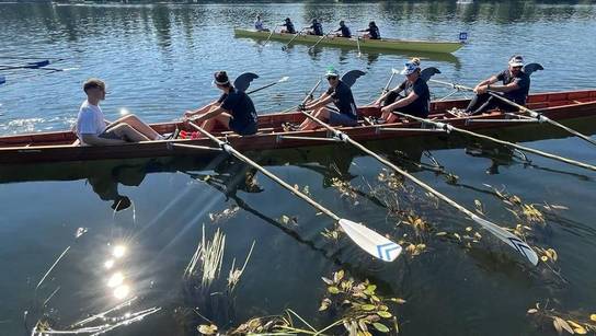 Ruderteam der SRH Schulen GmbH sitzt mit vier Ruderern und einem Steuermann im Ruderboot.